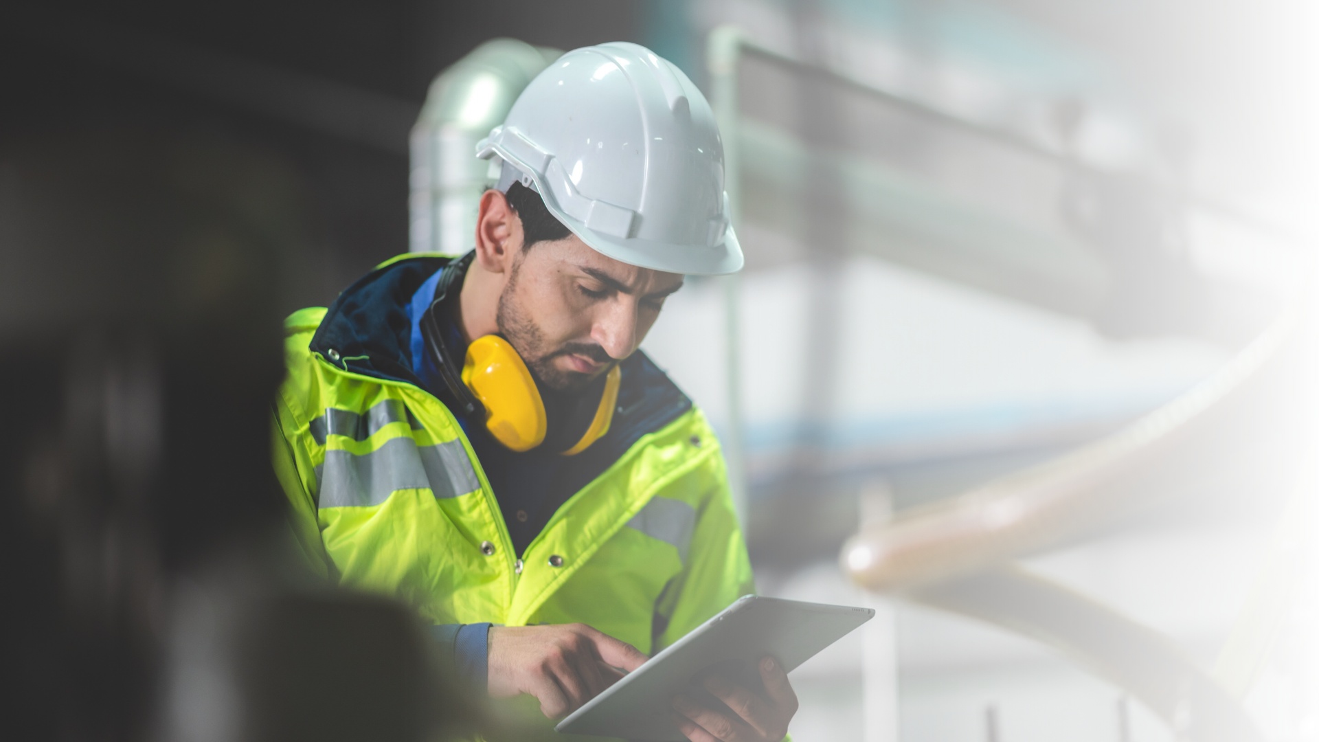 Monteur met veiligheidshelm en gehoorbescherming bekijkt een toolbox op een tablet